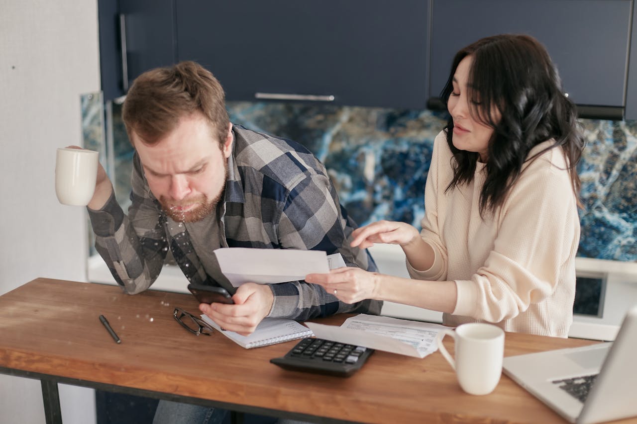 The Art of Drawing Readers In: Your attractive post title goes here A couple sitting at a desk, reviewing bills and expenses with a calculator and laptop, looking worried.